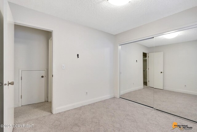 empty room featuring light carpet, baseboards, and a textured ceiling