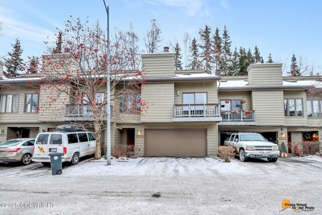 multi unit property featuring a garage, a chimney, and a balcony