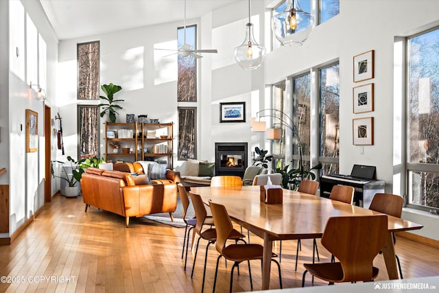 dining area featuring a high ceiling, ceiling fan, and light wood-type flooring