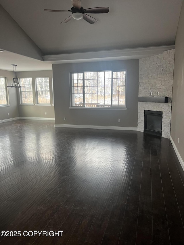 unfurnished living room with vaulted ceiling, a stone fireplace, dark hardwood / wood-style floors, and ceiling fan