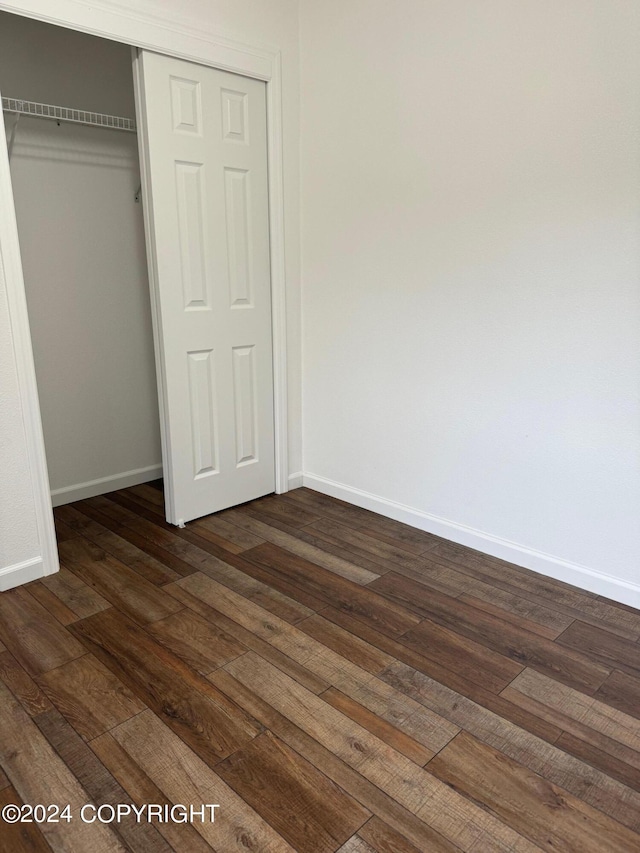 unfurnished bedroom featuring dark wood-type flooring and a closet