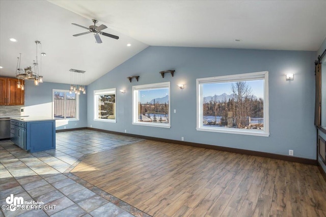 unfurnished living room featuring lofted ceiling, ceiling fan with notable chandelier, and light wood-type flooring