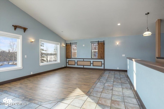 unfurnished living room with a barn door, high vaulted ceiling, and light hardwood / wood-style flooring