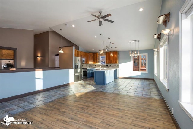 kitchen featuring hanging light fixtures, a center island, stainless steel refrigerator with ice dispenser, a kitchen bar, and washer / dryer