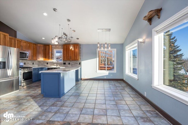 kitchen with lofted ceiling, appliances with stainless steel finishes, decorative backsplash, a kitchen island, and decorative light fixtures