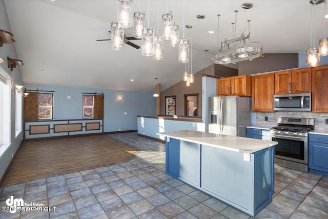 kitchen with appliances with stainless steel finishes, a breakfast bar, decorative light fixtures, a center island, and a barn door