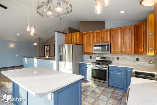 kitchen with vaulted ceiling, a kitchen island, appliances with stainless steel finishes, decorative light fixtures, and tasteful backsplash