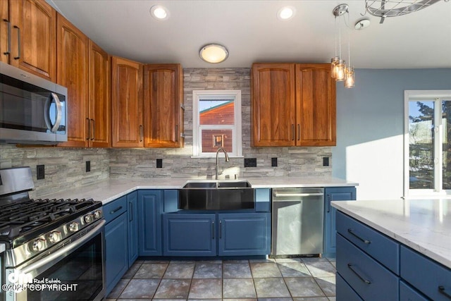 kitchen featuring pendant lighting, sink, stainless steel appliances, light stone countertops, and decorative backsplash