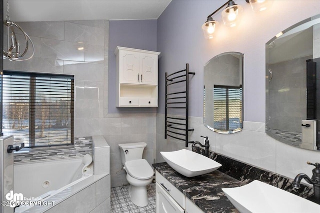 bathroom featuring radiator, tile walls, vanity, tiled bath, and toilet