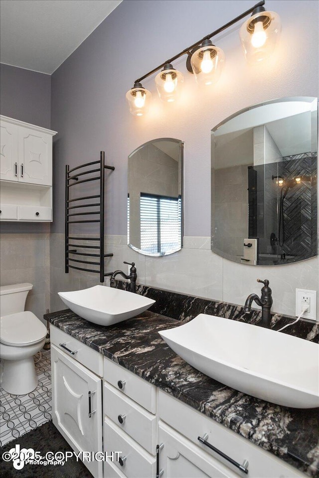 bathroom featuring vanity, radiator, toilet, and tile walls