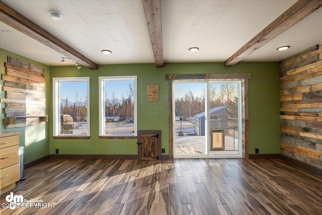 interior space with a textured ceiling, beamed ceiling, and a healthy amount of sunlight