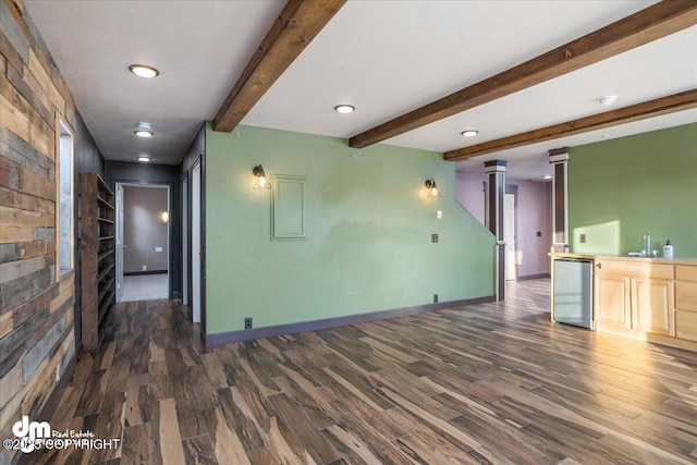 unfurnished living room with beamed ceiling, dark hardwood / wood-style floors, and decorative columns