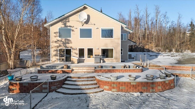 snow covered back of property with a deck