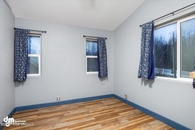 empty room with wood-type flooring and vaulted ceiling