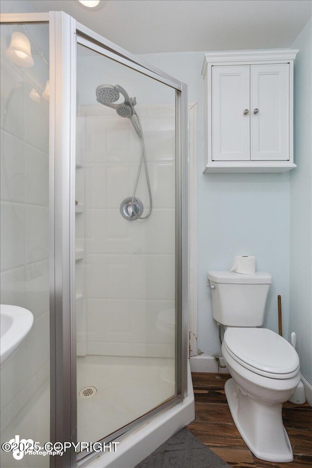 bathroom featuring a shower with door, wood-type flooring, and toilet