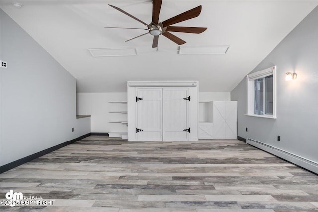 bonus room with ceiling fan, a baseboard heating unit, vaulted ceiling, and light wood-type flooring