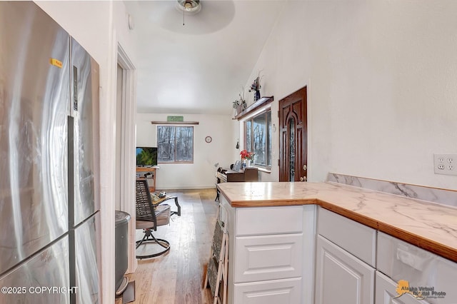 kitchen featuring white cabinetry, stainless steel fridge, ceiling fan, and light hardwood / wood-style flooring