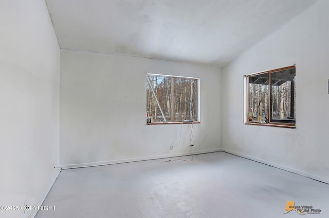 unfurnished room featuring lofted ceiling and concrete flooring