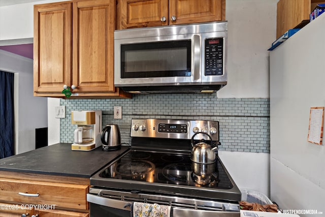 1510 E 40th Ct, Anchorage, AK 99508 - kitchen featuring stainless steel appliances, decorative backsplash, brown cabinets, and dark countertops