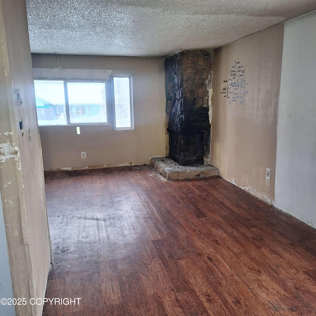 unfurnished living room featuring a fireplace, dark wood-type flooring, and a textured ceiling