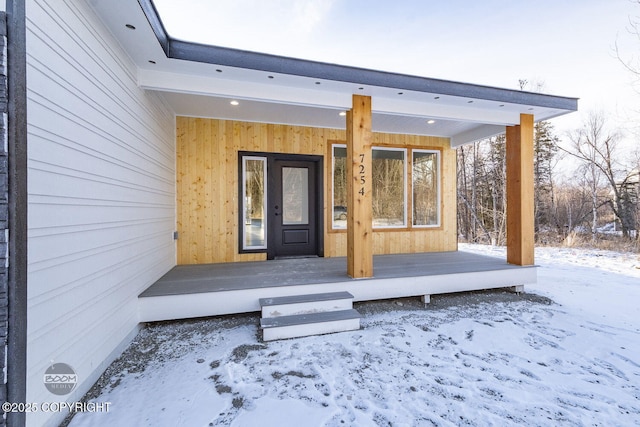 snow covered property entrance with covered porch