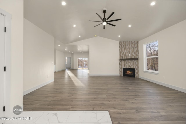 unfurnished living room with lofted ceiling, hardwood / wood-style floors, a stone fireplace, and ceiling fan