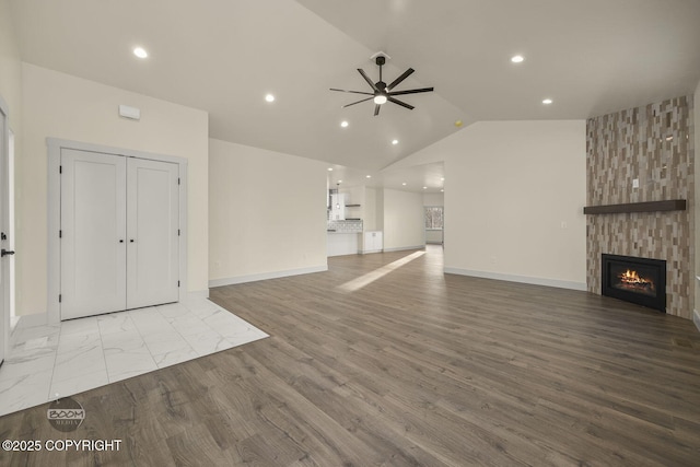 unfurnished living room featuring light hardwood / wood-style flooring, high vaulted ceiling, a large fireplace, and ceiling fan