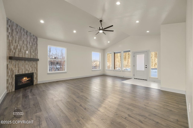 unfurnished living room featuring lofted ceiling, a large fireplace, dark hardwood / wood-style floors, and ceiling fan