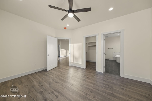 unfurnished bedroom featuring a walk in closet, connected bathroom, dark hardwood / wood-style flooring, and a closet