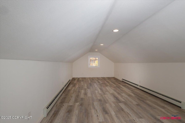 bonus room featuring lofted ceiling, light hardwood / wood-style floors, a textured ceiling, and a baseboard heating unit