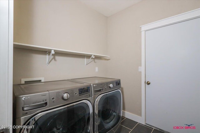 washroom featuring dark tile patterned flooring and washing machine and dryer