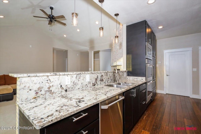 kitchen with sink, light stone counters, decorative light fixtures, dark hardwood / wood-style floors, and stainless steel appliances