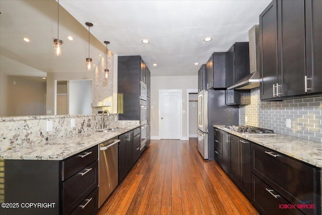 kitchen featuring light stone counters, appliances with stainless steel finishes, decorative light fixtures, and sink