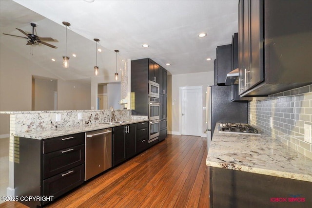 kitchen with appliances with stainless steel finishes, decorative light fixtures, sink, dark hardwood / wood-style flooring, and light stone counters