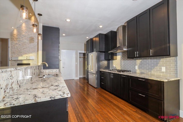 kitchen featuring sink, light stone counters, dark hardwood / wood-style flooring, stainless steel appliances, and wall chimney range hood