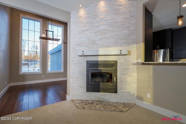 unfurnished living room featuring a stone fireplace and dark hardwood / wood-style flooring