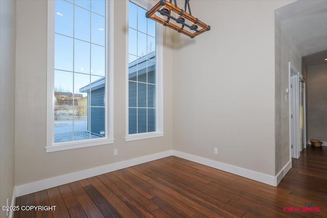 unfurnished room with dark wood-type flooring and a chandelier