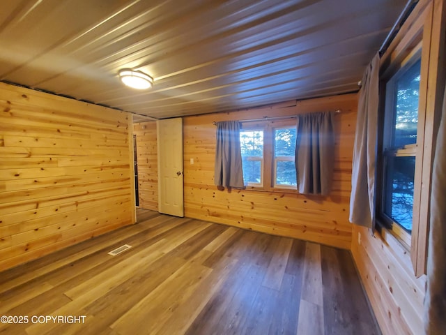 empty room featuring hardwood / wood-style flooring, wooden walls, and wooden ceiling