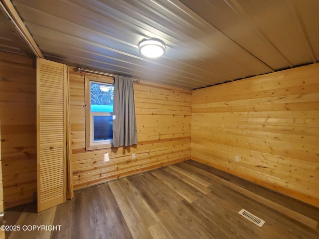 interior space featuring wooden walls, wooden ceiling, a closet, and wood-type flooring