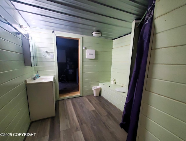 bathroom featuring vanity, hardwood / wood-style flooring, wooden walls, and walk in shower