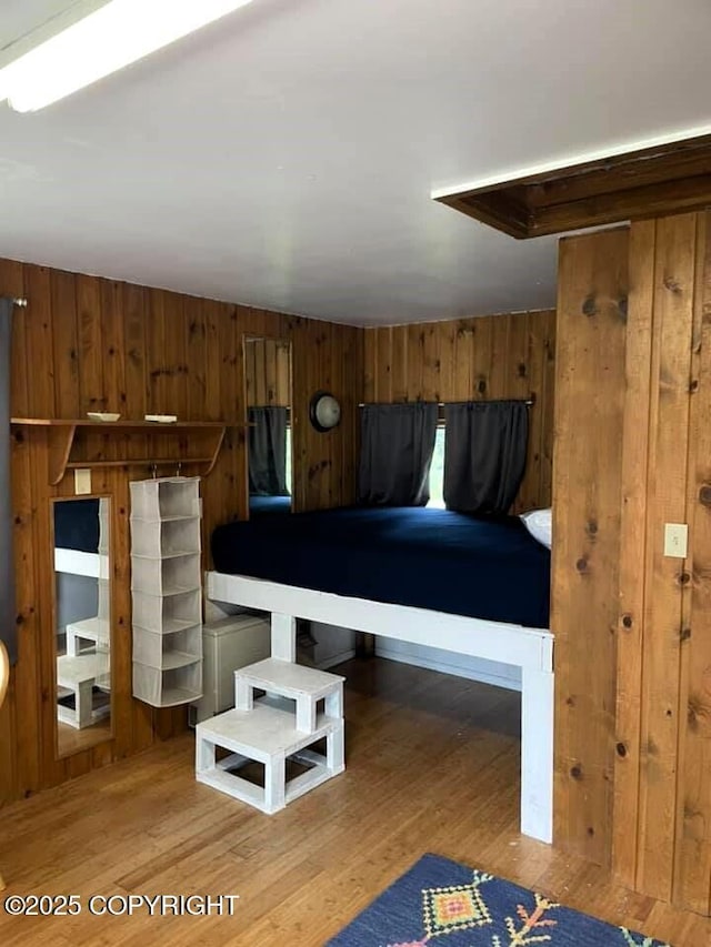 unfurnished bedroom featuring hardwood / wood-style flooring and wooden walls