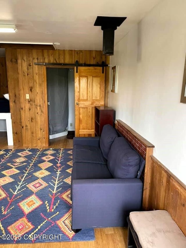 unfurnished living room with dark hardwood / wood-style flooring, a barn door, and wooden walls