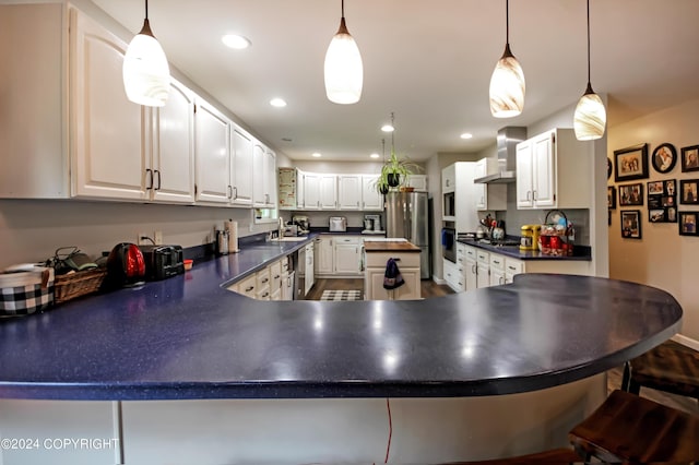 kitchen with white cabinetry, kitchen peninsula, hanging light fixtures, stainless steel fridge, and sink