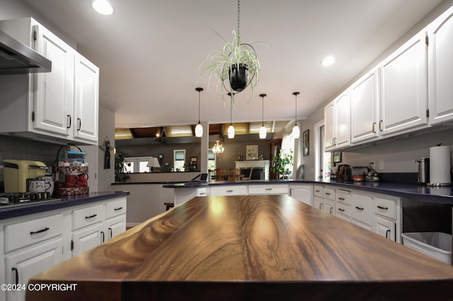 kitchen featuring hanging light fixtures, extractor fan, gas stovetop, white cabinetry, and kitchen peninsula