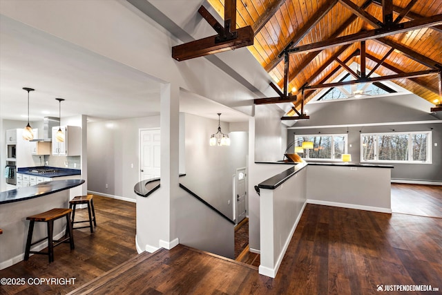 stairs featuring wood-type flooring, a notable chandelier, baseboard heating, wood ceiling, and lofted ceiling with beams