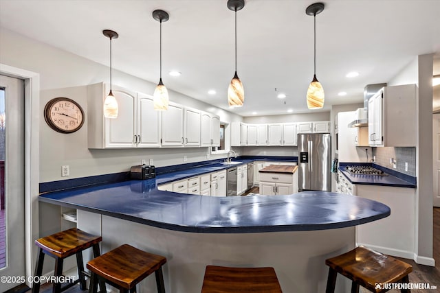 kitchen with appliances with stainless steel finishes, a kitchen breakfast bar, tasteful backsplash, and white cabinets