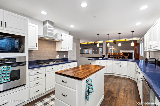 kitchen featuring white cabinetry, kitchen peninsula, stainless steel appliances, and wall chimney exhaust hood