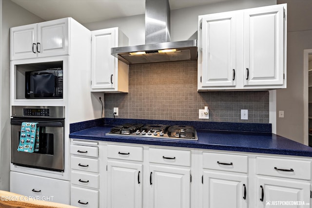 kitchen featuring wall chimney range hood, white cabinets, stainless steel appliances, and decorative backsplash