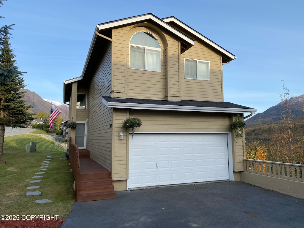 view of front of home featuring a garage, a mountain view, and a front lawn