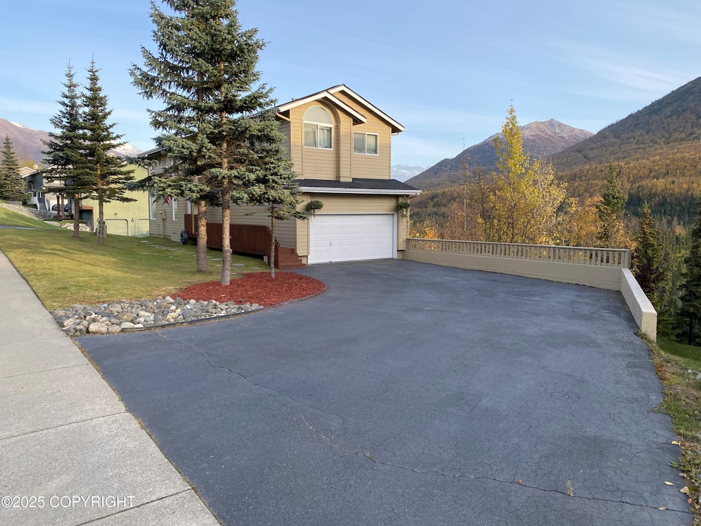 view of side of home with a mountain view, a garage, and a yard